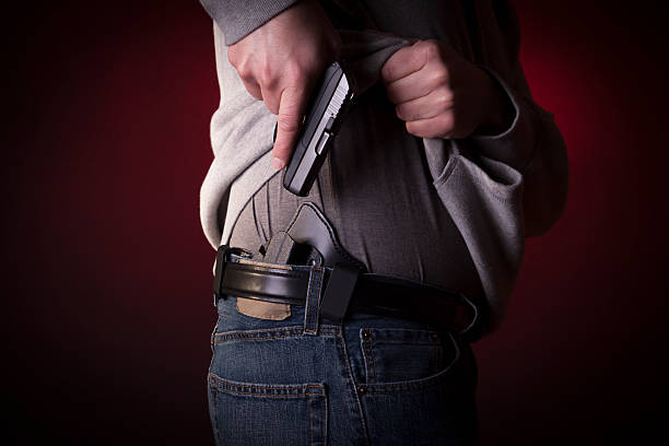 A man drawing a conceal carry pistol from an inside the waistband holster IWB.